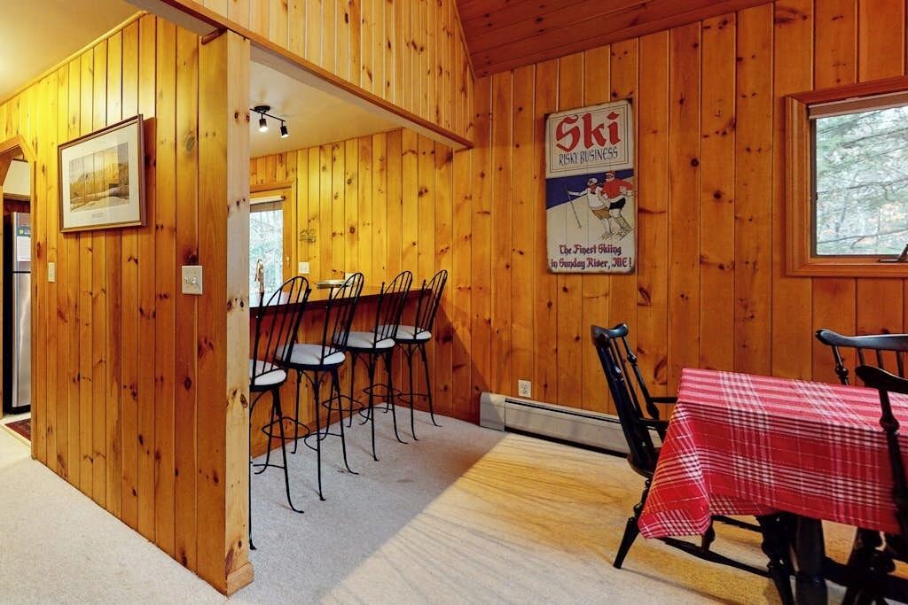 A wooden interior with a dining area, a ski-themed sign, and a window.