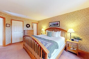 A bedroom with a wooden bed, two bedside tables with lamps, a dresser, and a door. - Cute townhome on the slopes with trail access, deck, hot tub & pool (Newry)