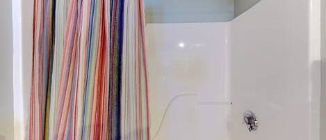 Eine Dusche mit weißer Wand und bunter Duschvorhang.