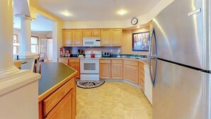 A kitchen with wooden cabinets, a stainless steel refrigerator, a microwave, and a stove. - Cute townhome on the slopes with trail access, deck, hot tub & pool (Newry)