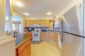A kitchen with wooden cabinets, a stainless steel refrigerator, a microwave, and a stove. - Cute townhome on the slopes with trail access, deck, hot tub & pool (Newry)