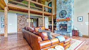 A spacious living area with a stone fireplace, wooden beams, and a leather sofa. - Stunning mountain-view estate with private pool & hot tub - near slopes (Newry)