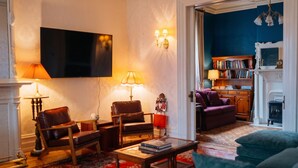 A living room with a flat-screen TV, two leather chairs, a coffee table, and a bookshelf. - The Hillard - A Private Historic Estate 1865 (Wilkes-Barre)
