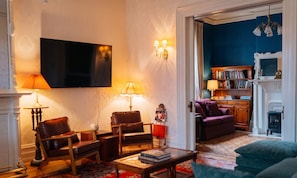 Una sala de estar con una televisión de pantalla plana, dos sillones de cuero, una mesa de centro y una estantería.