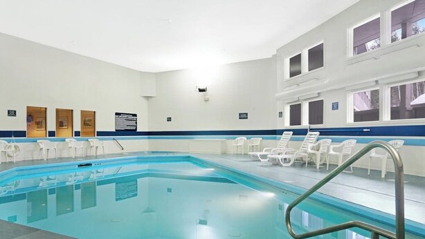 An indoor swimming pool with clear water, surrounded by white lounge chairs, and a blue and white tiled floor. - Ski-in/ski-out condo with shared pool & hot tub - steps away from ski lift (Newry)