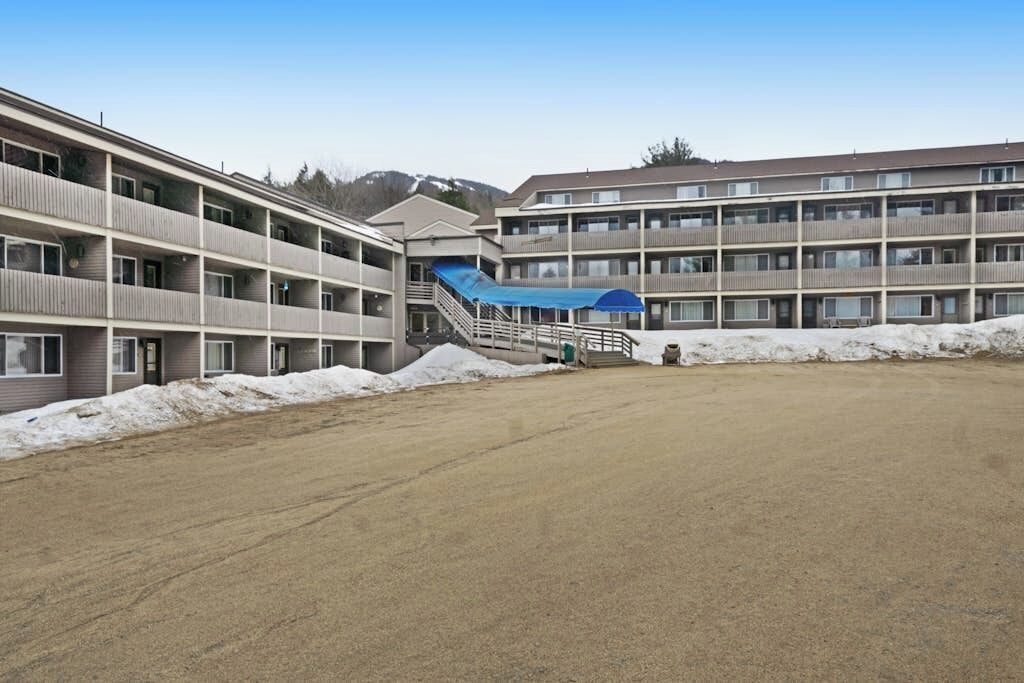 A multi-story motel with a covered outdoor area and a parking lot.