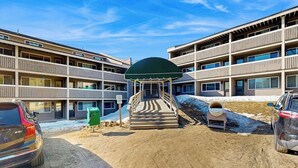A multi-story building with a central staircase leading to a covered area, surrounded by parking spaces. - Ski-in/ski-out condo with shared pool & hot tub - steps away from ski lift (Newry)