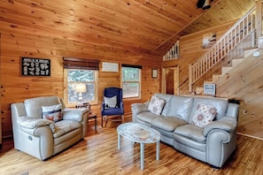 Ein Holzblockhaus-Interieur mit einer Couch, einem Sessel und einem kleinen Tisch.