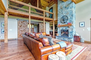 Ein geräumiger Wohnbereich mit Ledersofa, Kamin aus Stein und Holzbalkon.