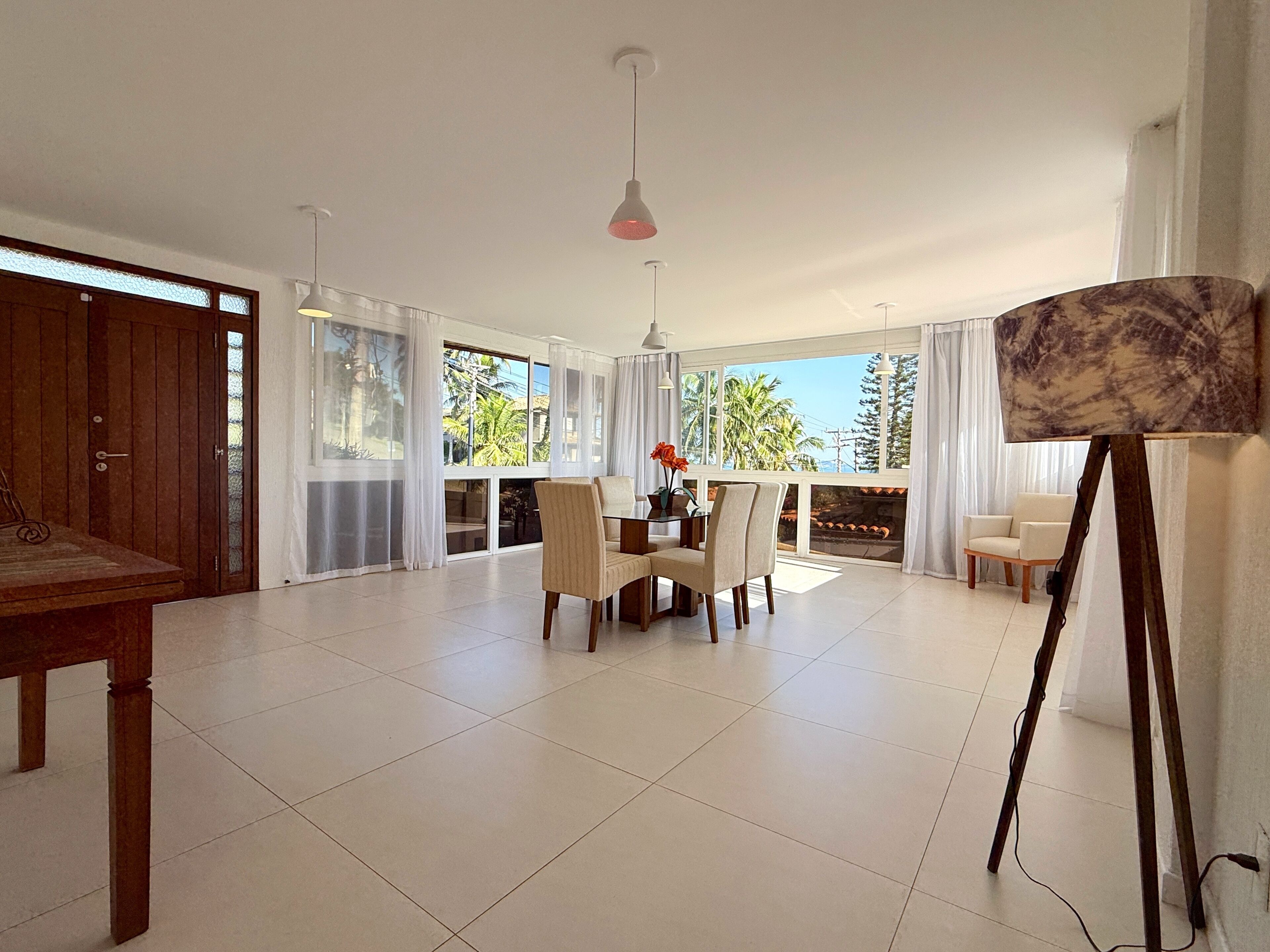 A spacious room with a dining area, large windows, and a ceiling light fixture.