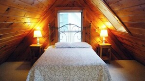 A bedroom with a bed, two bedside lamps, a window, and wooden walls. - Dog-Friendly Lakefront Cottage w/Lake Access, Deck, Gas Grill, A/C (Standish)