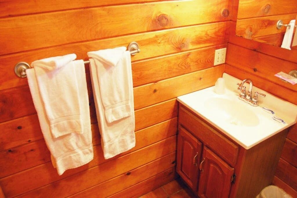Un baño con paneles de madera, un lavabo, un espejo y un perchero para toallas.