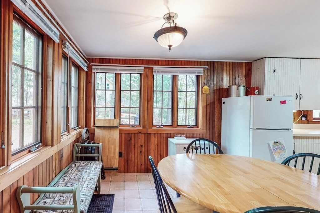 Une cuisine aux murs lambrés, avec une table à manger, des chaises et un banc.
