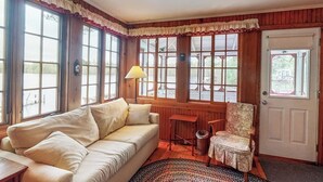 Una habitación acogedora con sofá, sillón, lámpara y ventanas amplias con vistas.