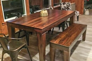 A wooden dining table with chairs and a bench, set in a room with wooden walls and a window. - Private waterfront cabin with large deck, private dock, kayaks & gas grill (Naples)