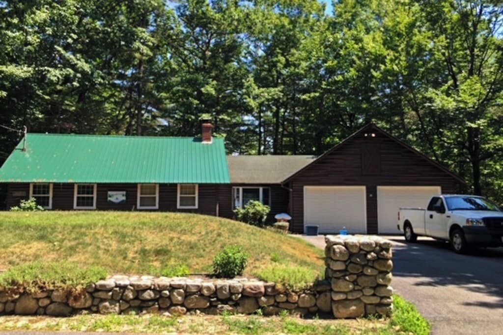 A cabin with a green roof, a stone wall, and a parked truck.