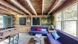 Una habitación acogedora con mesa de fútbol, sofá y zona de bar con botellas.