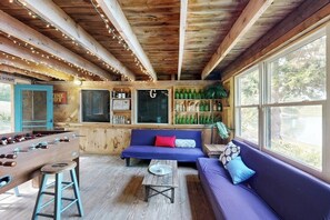 Una habitación acogedora con mesa de fútbol, sofá y zona de bar con botellas.