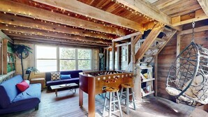 Una habitación acogedora con una mesa de futbolín, un sillón colgante y una escalera.