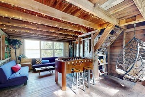 Una habitación acogedora con una mesa de futbolín, un sillón colgante y una escalera.