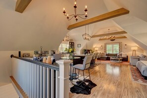 Ein geräumiger Loft mit hohen Decken, freiliegenden Holzbalken, einem Essbereich und einer gemütlichen Sitzecke.