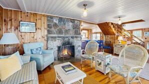 Un interior acogedor con chimenea de piedra, paredes de madera y una escalera.
