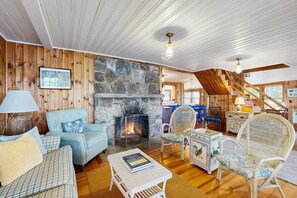 A cozy interior with a stone fireplace, wooden walls, and a staircase. - Naples Lakefront Retreat | Private Beach, Dock & Kayaks | Family + Dog friendly (Naples)