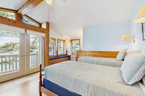 A bedroom with a large bed, a wooden headboard, a window with a view, and a balcony.