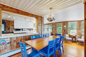 A wooden interior with a dining area, kitchen, and seating by a window.