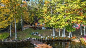 A lakeside cabin with a dock, surrounded by autumn foliage. - Lakefront, dog-friendly home with dock, kayaks, SUPs, canoe, huge deck & firepit (Norway)