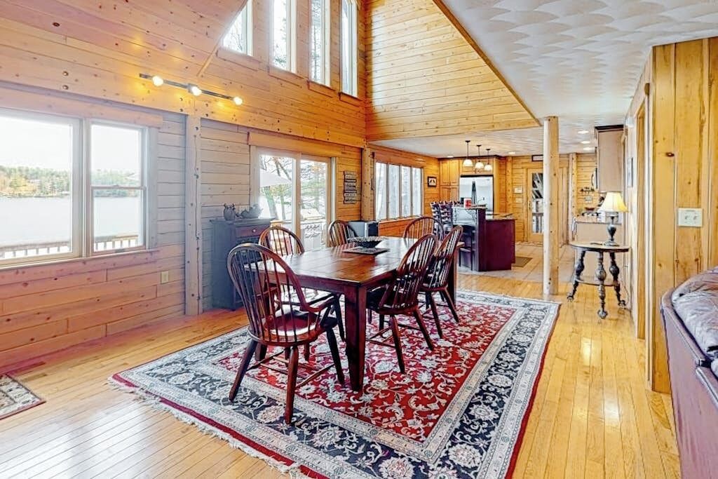 L’intérieur d’un chalet en bois comprend un coin repas, de grandes fenêtres et une vue sur l’extérieur.