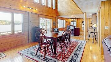 L’intérieur d’un chalet en bois comprend un coin repas, de grandes fenêtres et une vue sur l’extérieur.