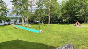 Eine Rasenfläche mit Schwimmbad, Liegestühlen und einem kleinen, hausähnlichen Gebäude.