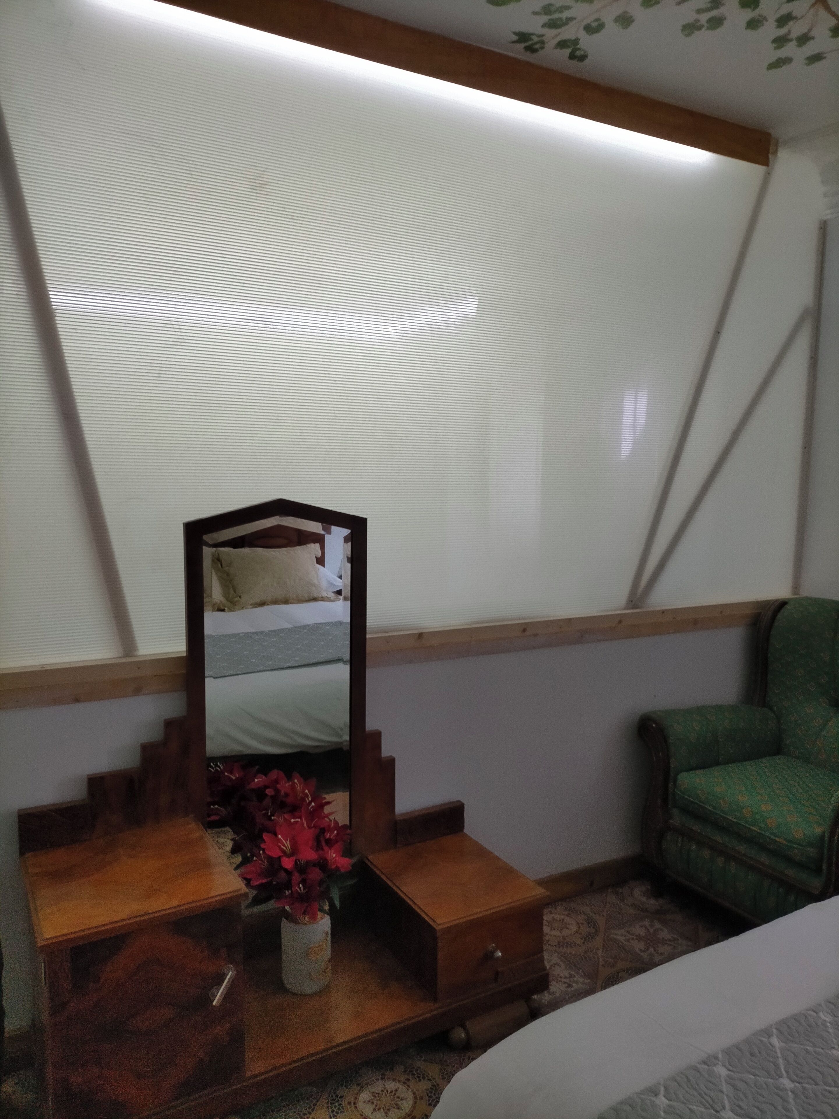 Un dormitorio con una cama, un aparador de madera, un espejo y una silla verde.