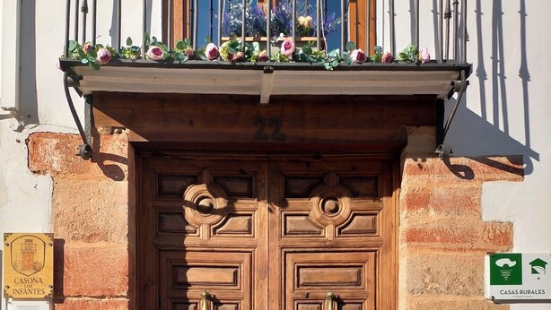 A wooden double door with a number '22' above it, a balcony with flowers, and a sign indicating 'CASA RURAL.' - Renovated historic house in the center of Vva.de los Infantes. Groups and couples. (Villanueva de los Infantes)