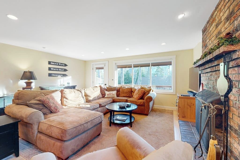 A cozy living room with a sectional sofa, a round coffee table, and a fireplace.