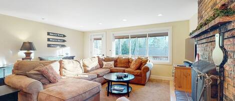 A cozy living room with a sectional sofa, a round coffee table, and a fireplace.
