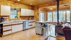 Een houten hut interieur met een keuken, een eethoek en een groot raam.
