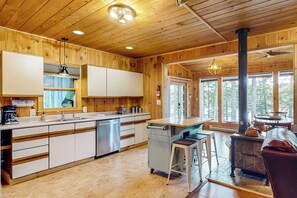 Ein Interieur einer Holzhütte mit Küche, Essbereich und einem großen Fenster.
