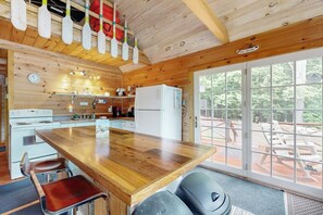 A wooden interior with a kitchen, dining area, and large windows.