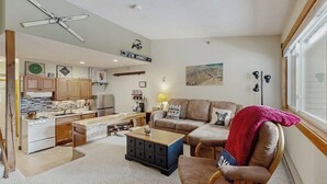 A compact living space with a kitchenette, a sofa, a coffee table, and a dining area. - Ski-in/out 2-story condo with balcony, on-site indoor pool, hot tub, sauna, W/D (Newry)
