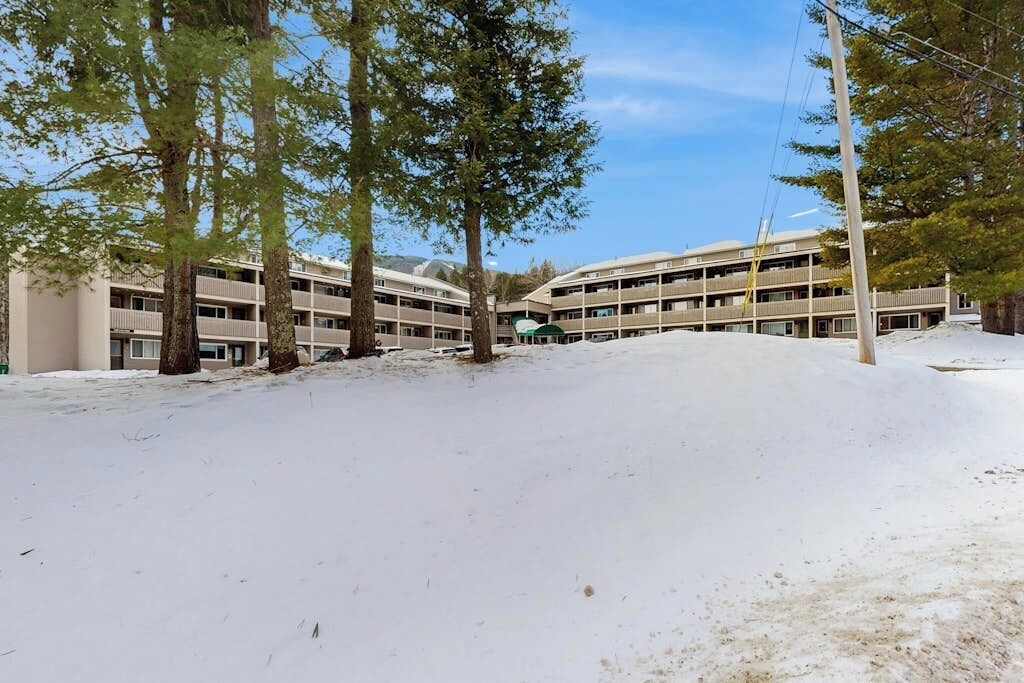 A multi-story hotel with a parking lot and trees.