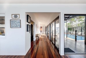 A modern hallway with wooden flooring, a bench, and a sign on the wall. - Dogs welcome @ Beachside Beauty - 31 Tristania Drive (Noosa)