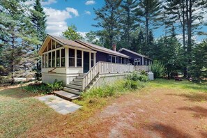 Eine Hütte mit Veranda, Treppe und Blick auf den umliegenden Wald.