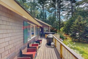 Eine Holzterrasse mit Sitzgelegenheit, einem Whirlpool und einem Grill.
