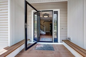 Entrada d'una casa amb una porta corredissa de vidre, un felpudet i una escala que porta a l'interior.