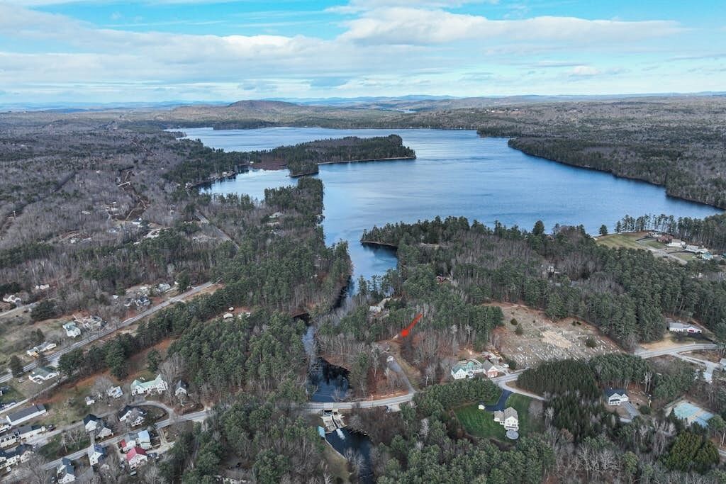 Luchtbeeld van een meer, omgeven door dichte bossen en woonwijken.