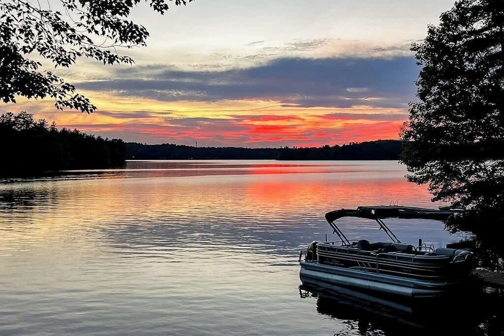 A calm lake at sunset with a boat docked on the right.