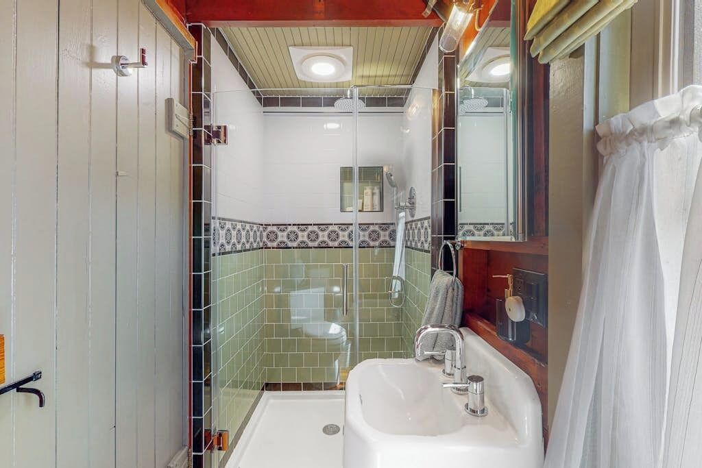 A bathroom with a shower, a sink, and a mirror.