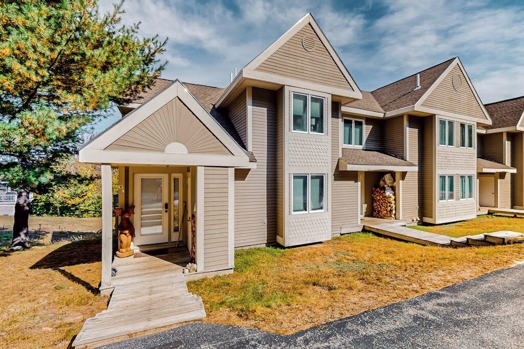 A residential building with a central entrance, multiple windows, and a covered porch.